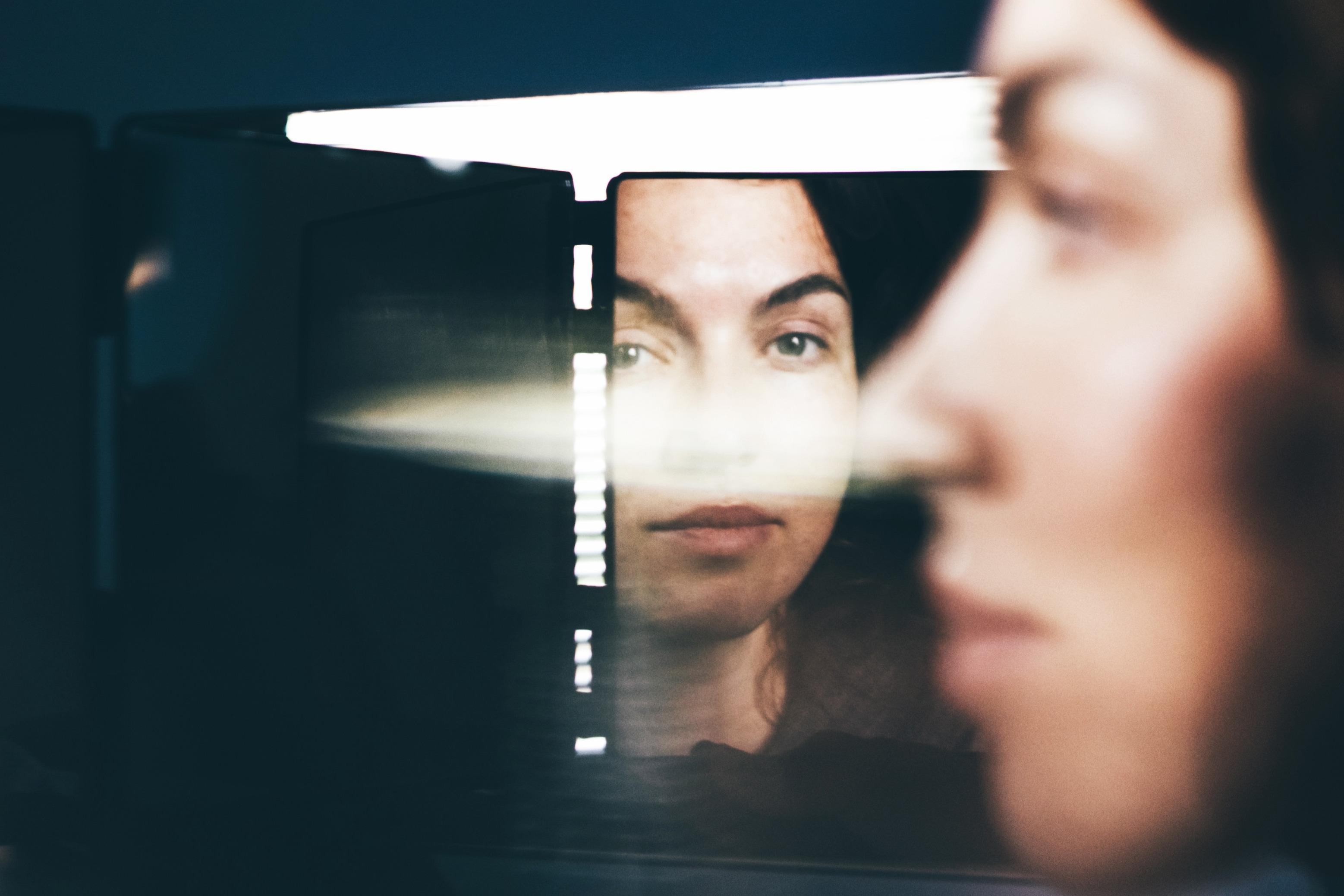 A person is looking away from a mirrow, while the reflection is looking at them.