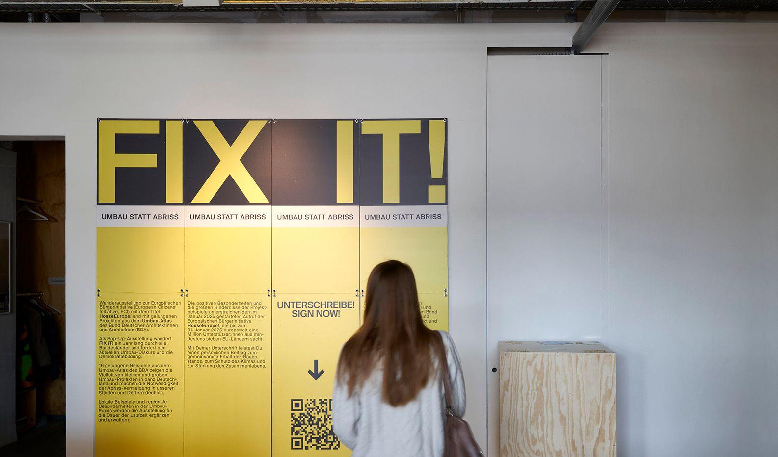 A woman stands in the exhibition and reads a poster