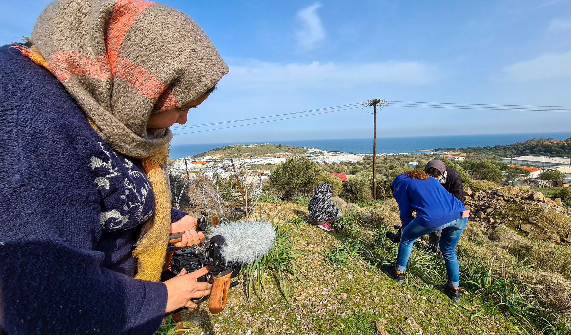 Two women are outside on Lesvos and are filming in the landscape.