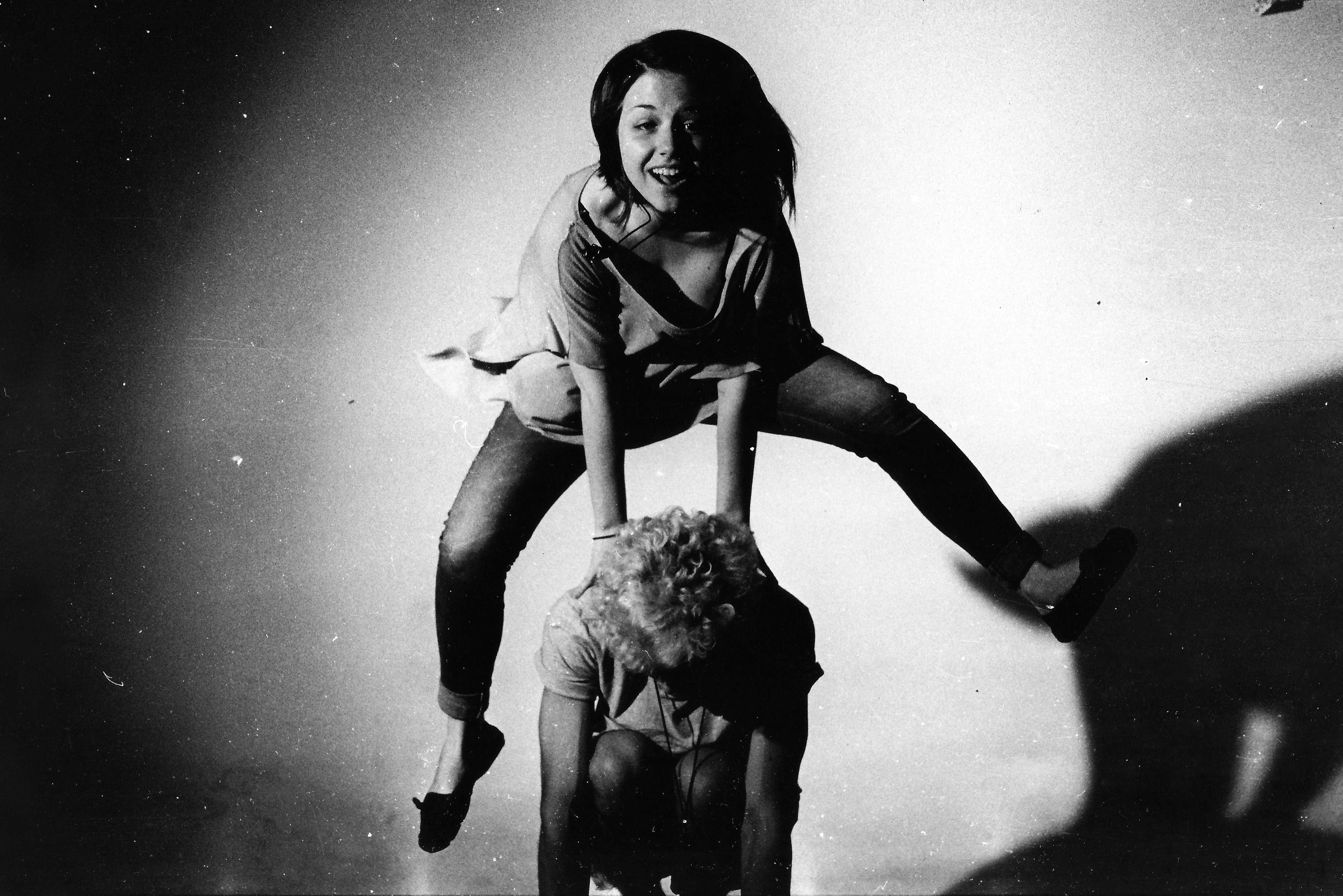 Frau, die auf den Rücken einer anderen Person springt in, dargestellt in Graustufenfotografie 