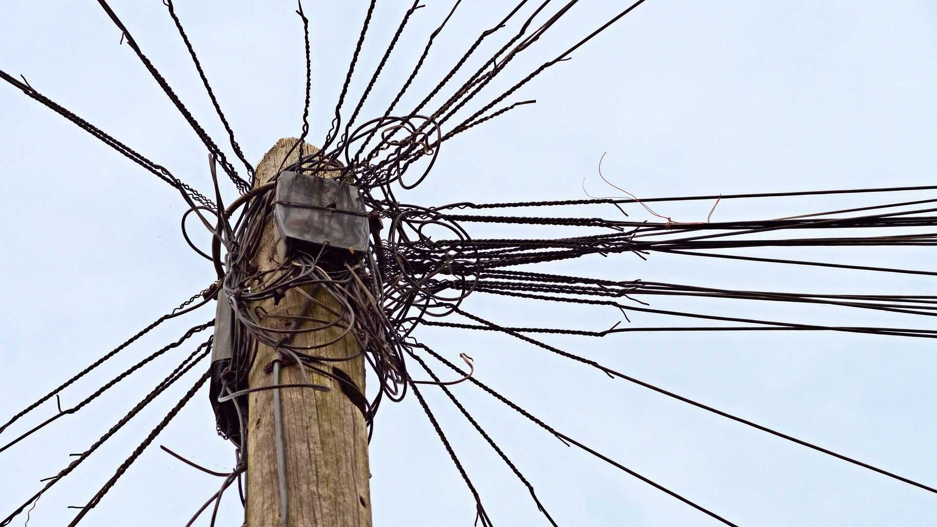 A wooden power pole with many electric wires