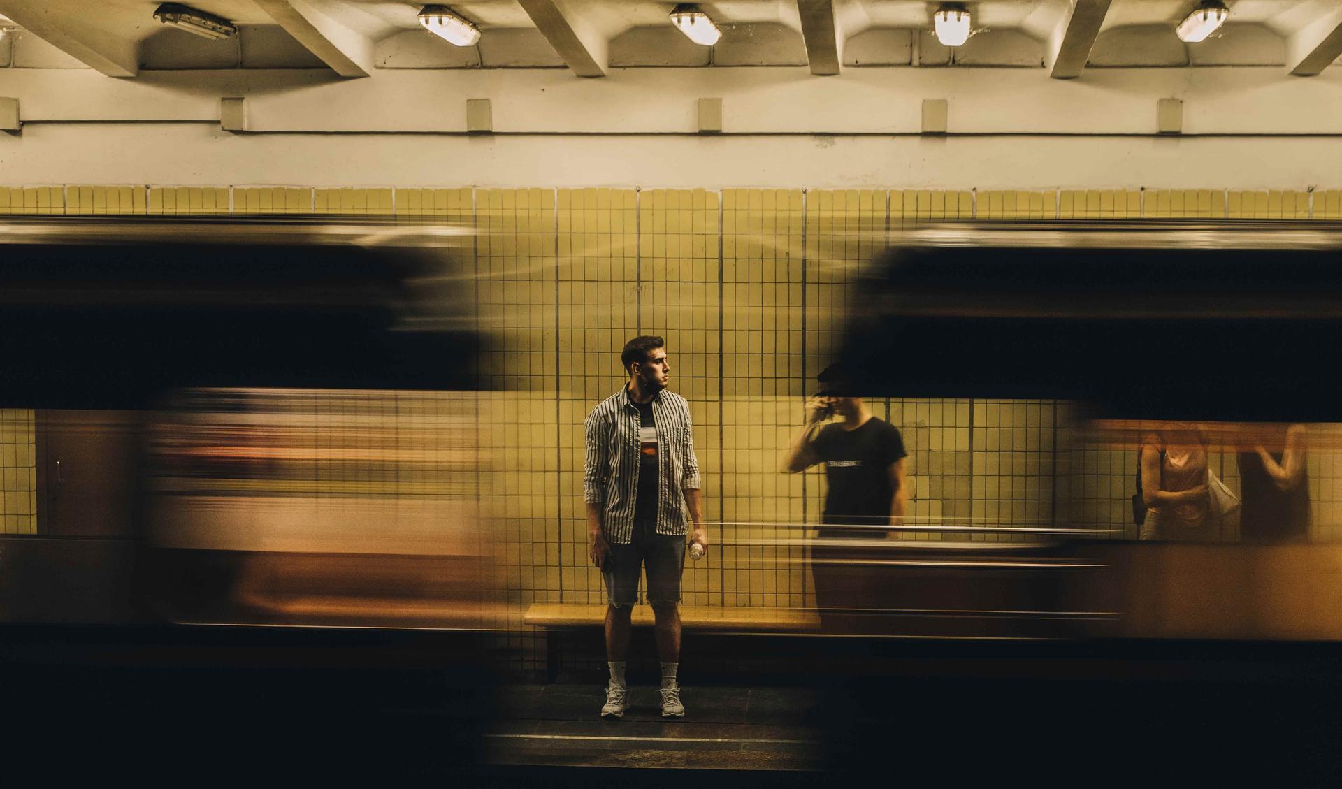 A person is standing on a underground platform and a train is passing by.