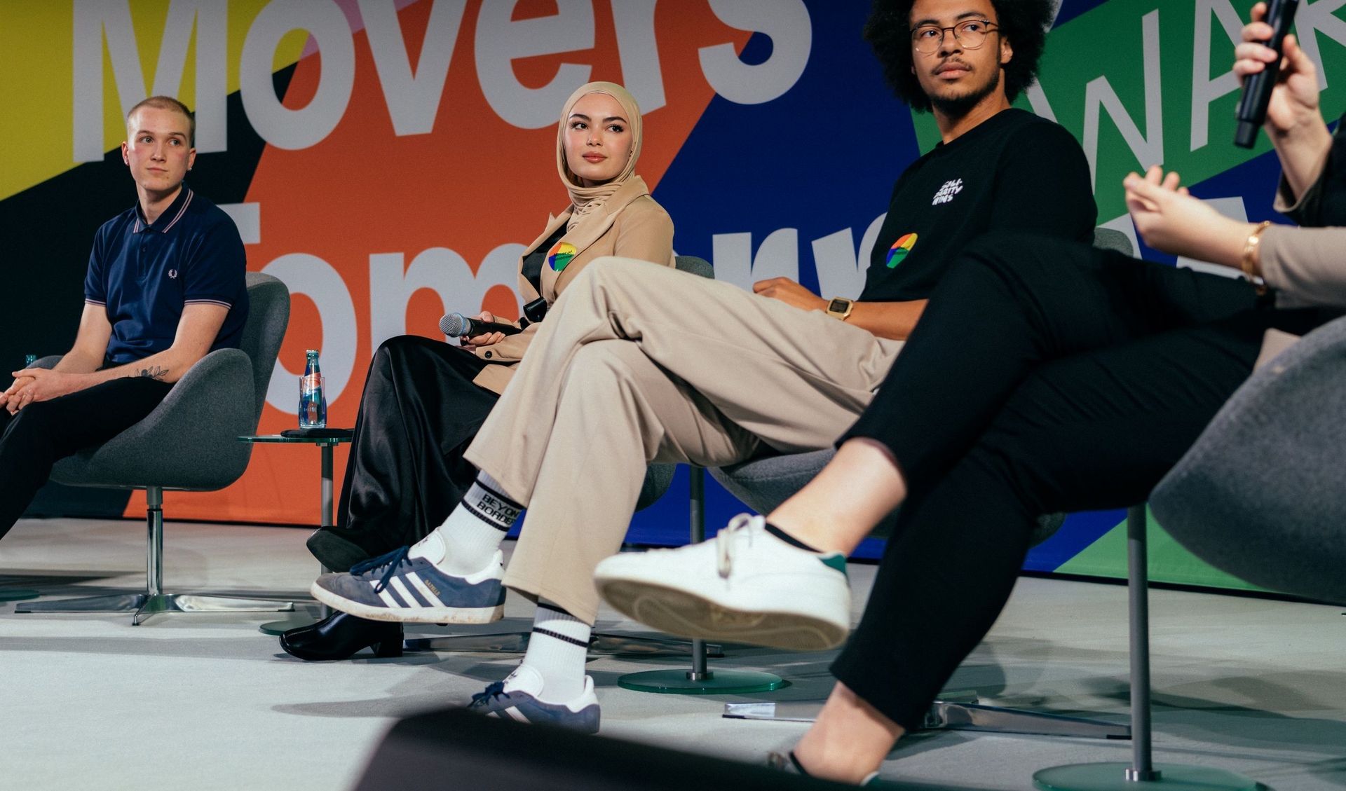 Four young people are sitting on a stage and are discussing with each others during a panel talk