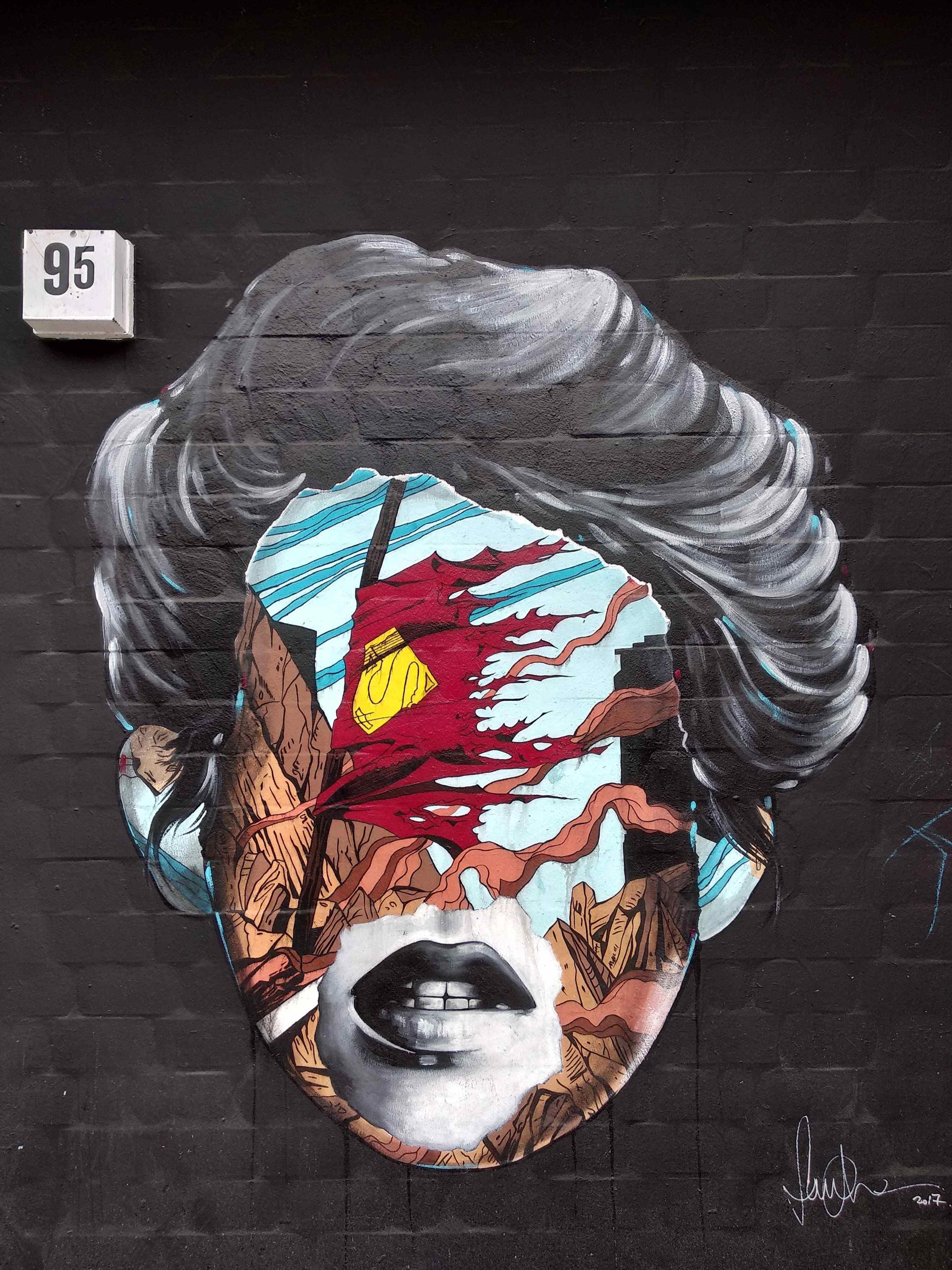 A mural with a face of a woman that has comic strips put over her face