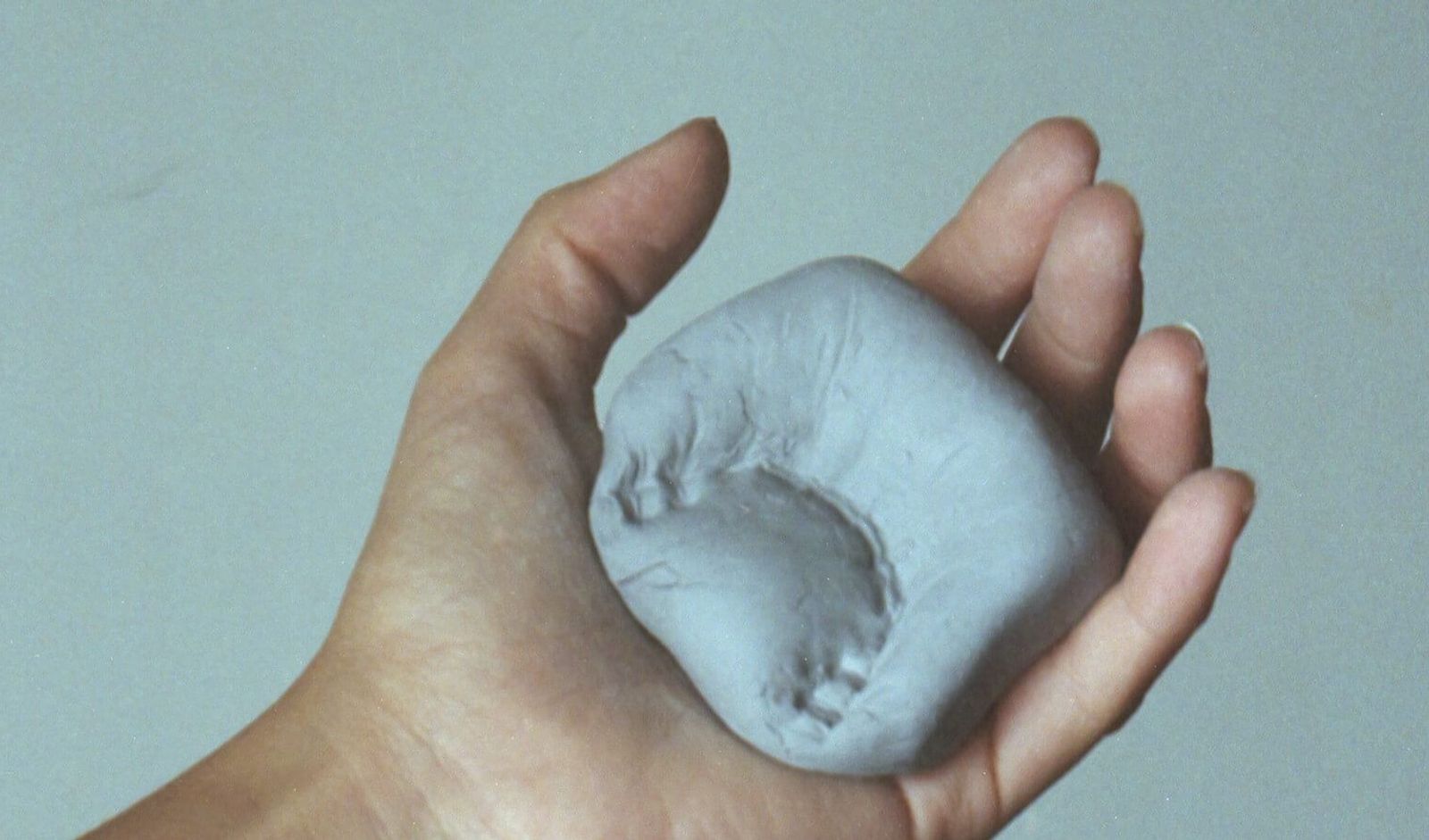 A hand holding a substance with a dental impression on it