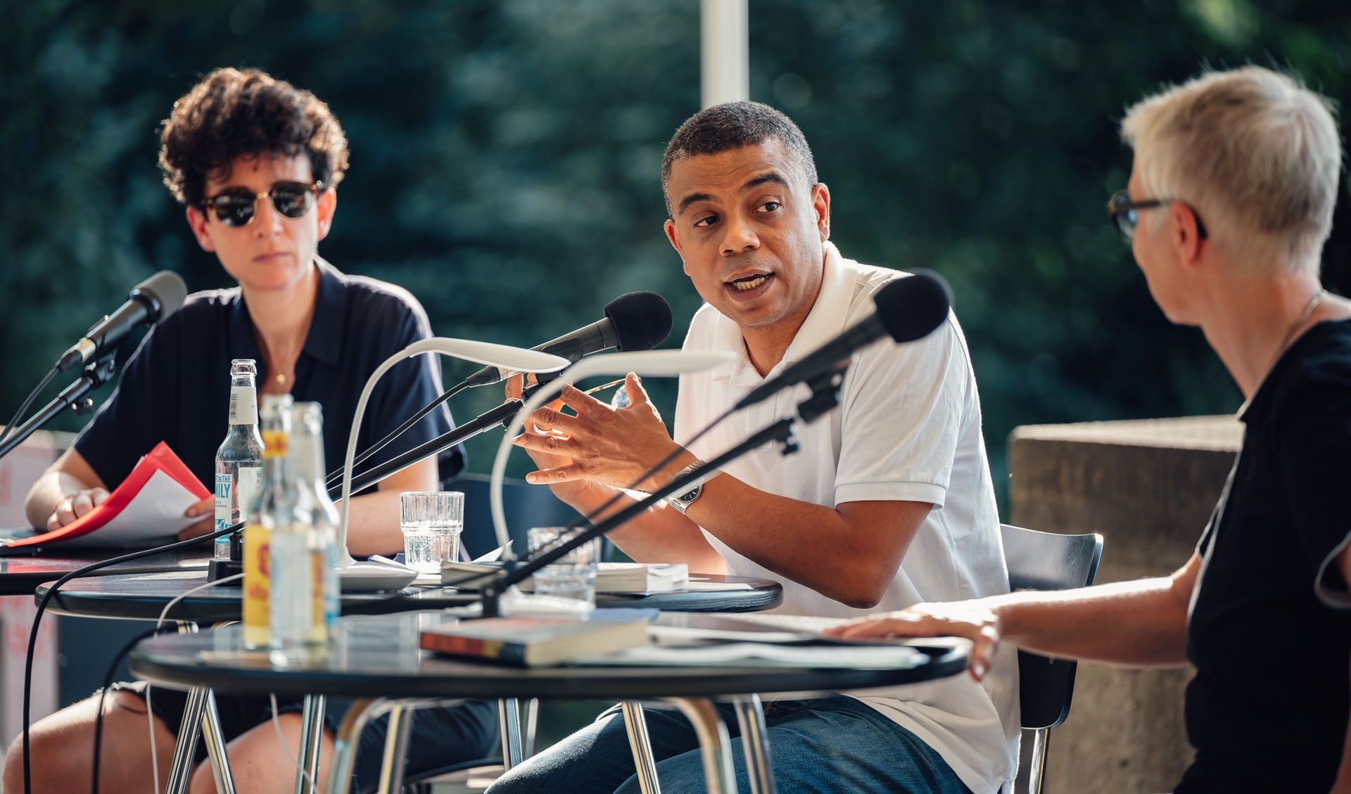 Three people are having a discussion on an outside located panel in summer