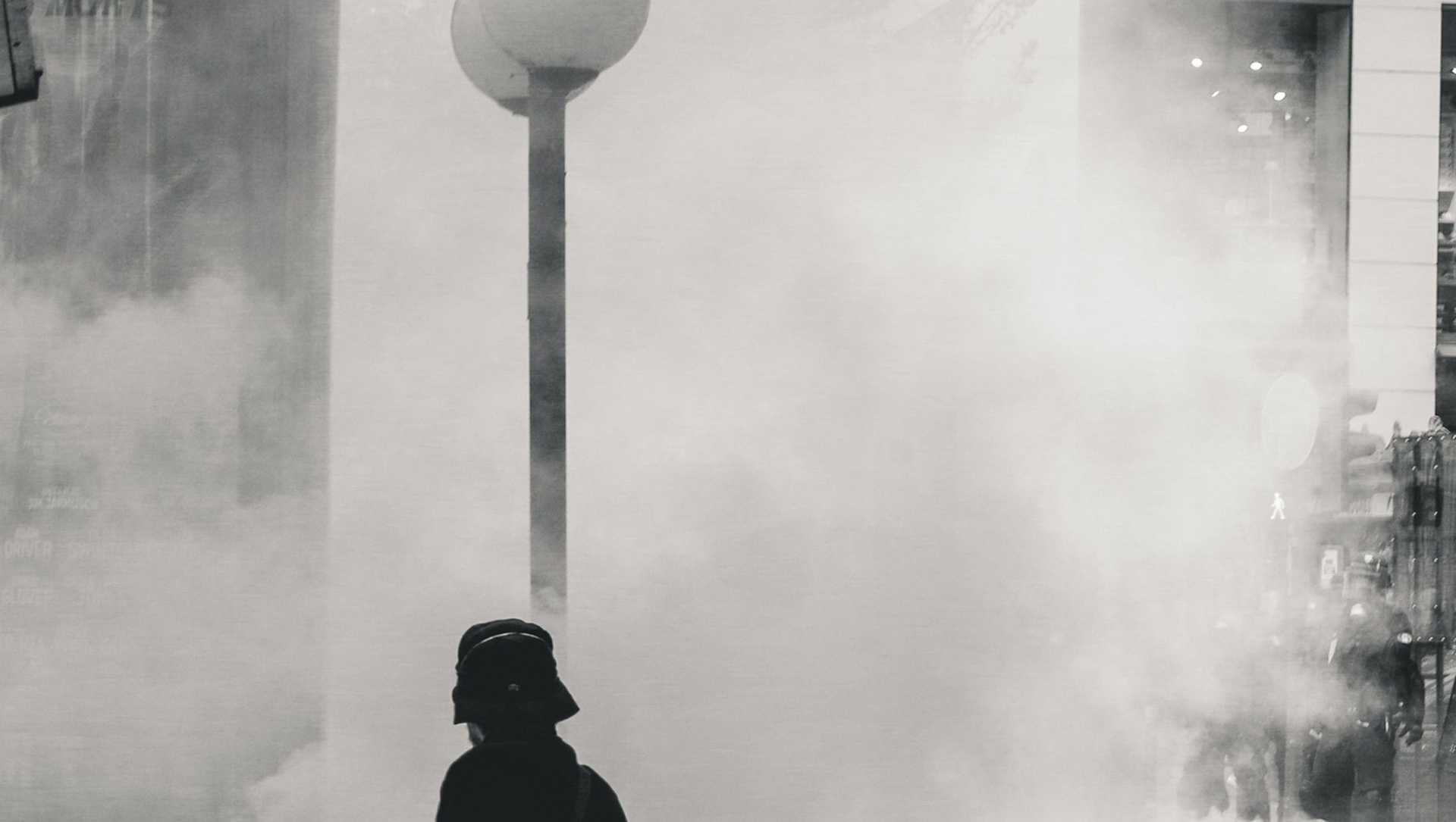 A person during a protest is covered by smoke