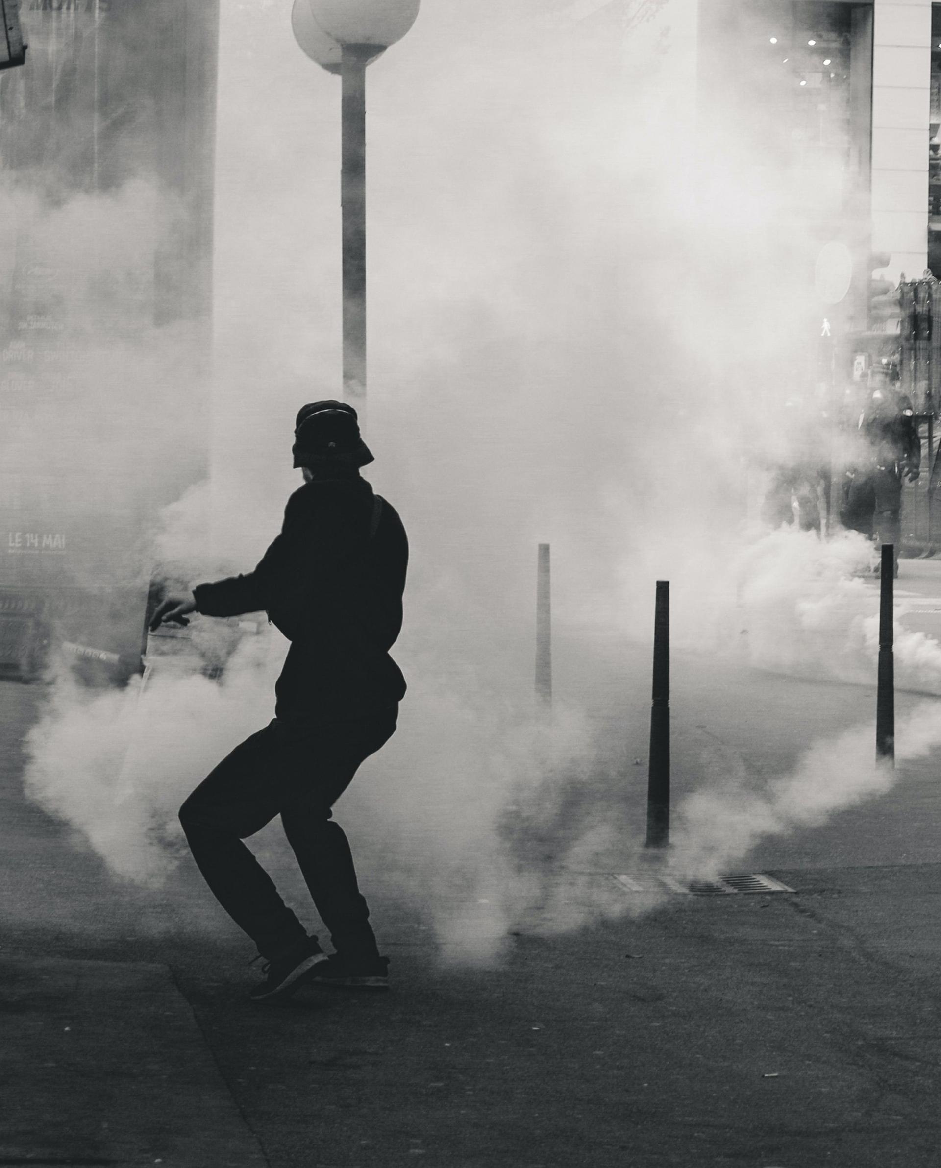 A person during a protest is covered by smoke