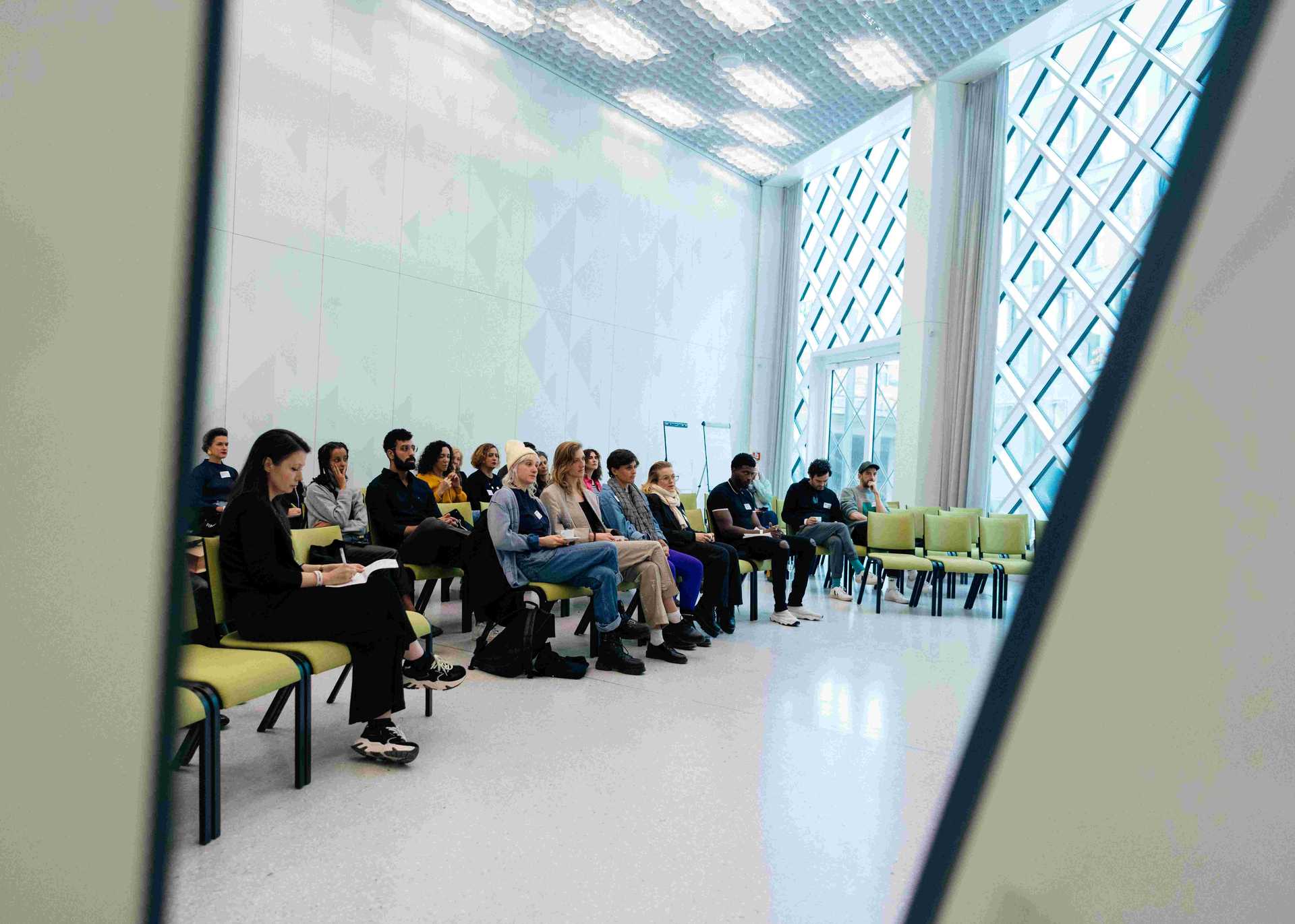 A crowd in a workshop room is listening to the speaker.