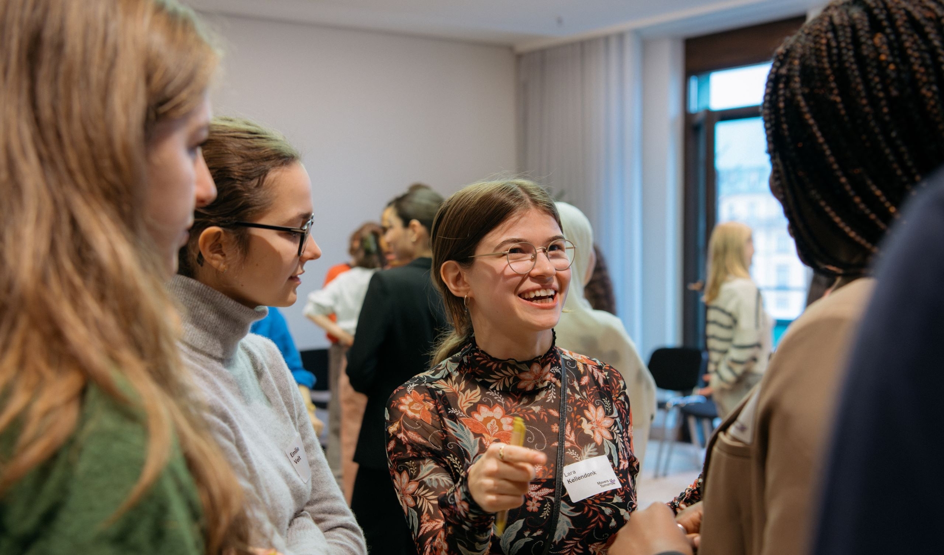 Young people standing in a room, laughing and talking