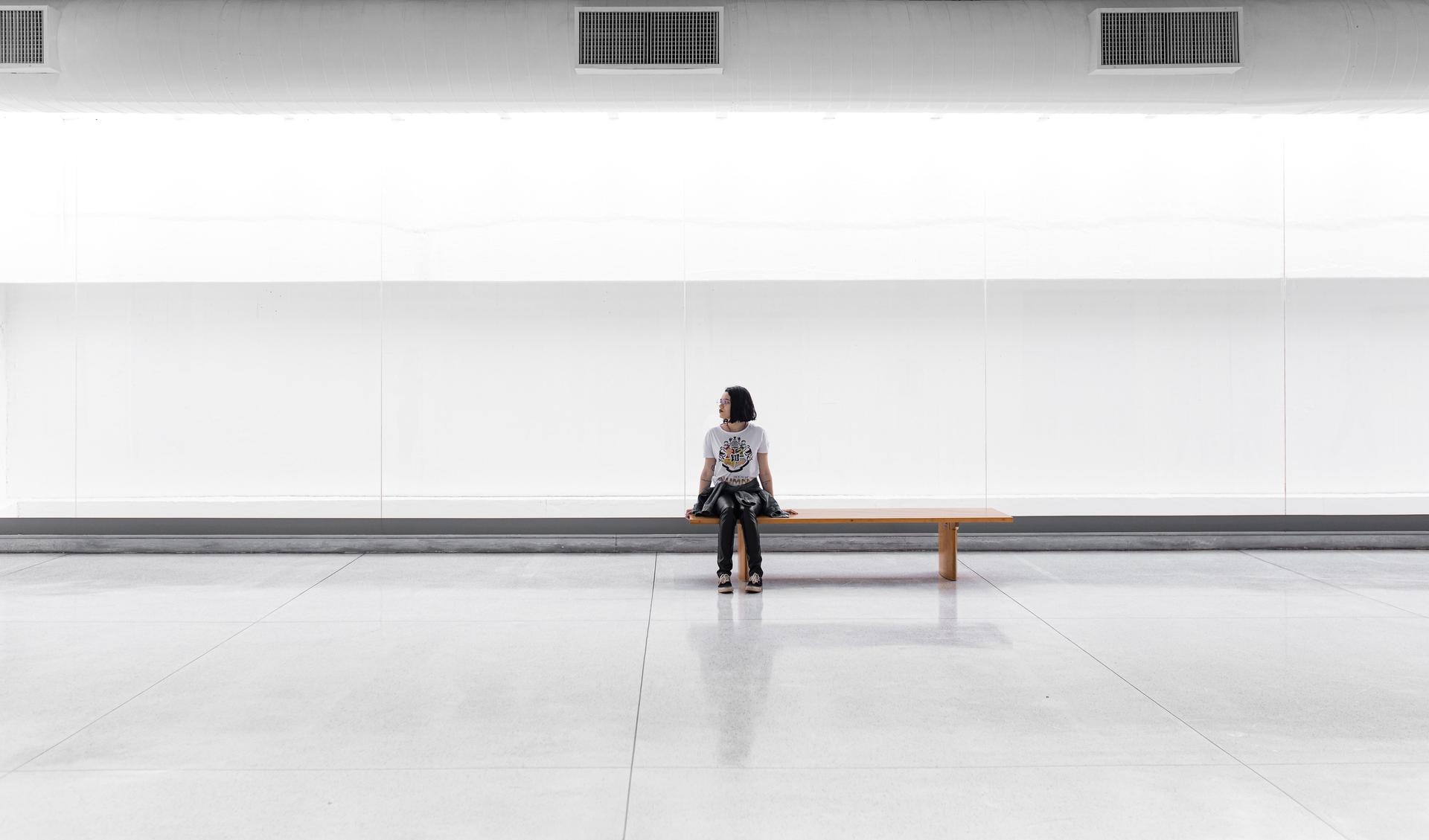 A woman sits on a bench and looks into the room