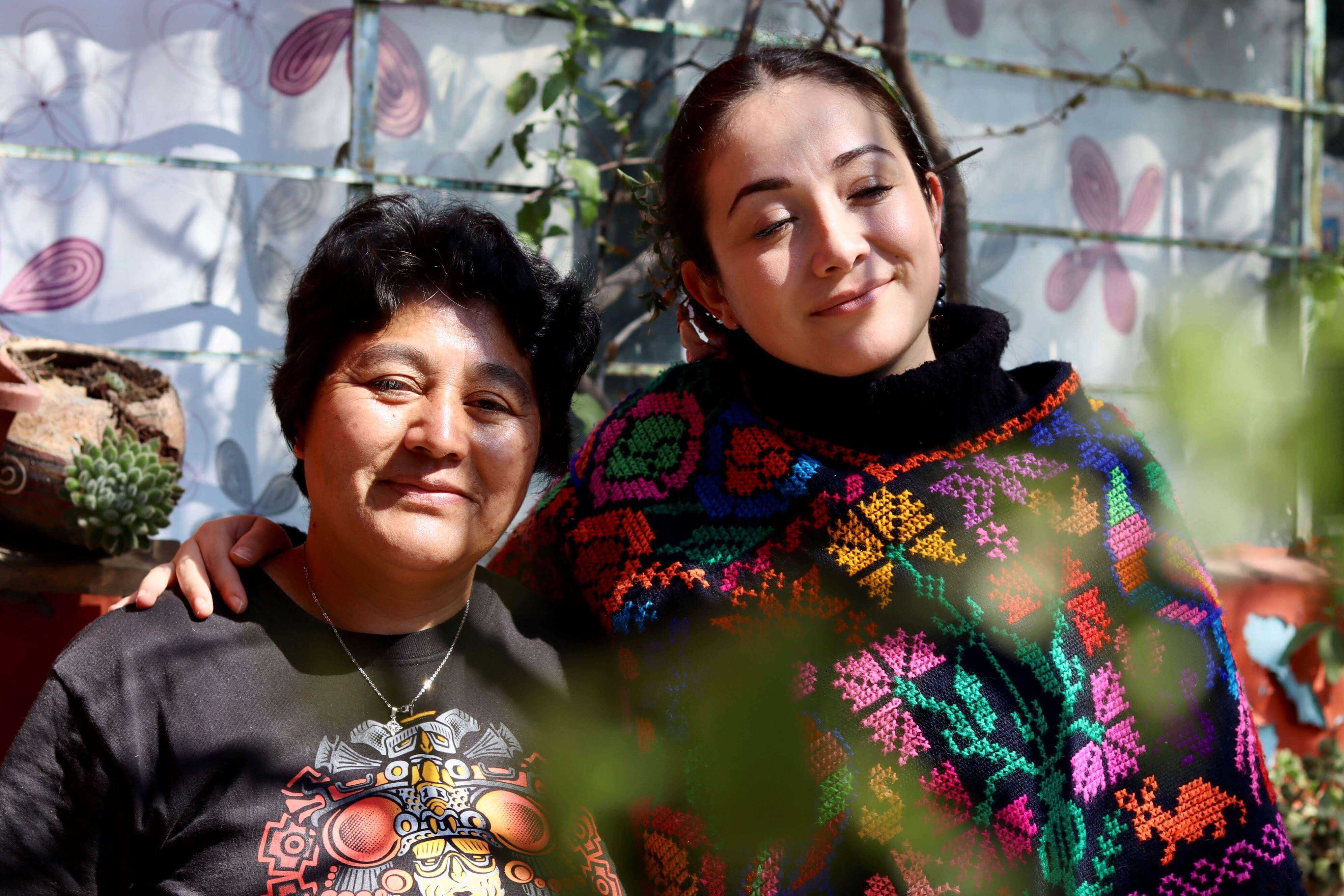 Two persons are sitting next to each other and are looking into the camera