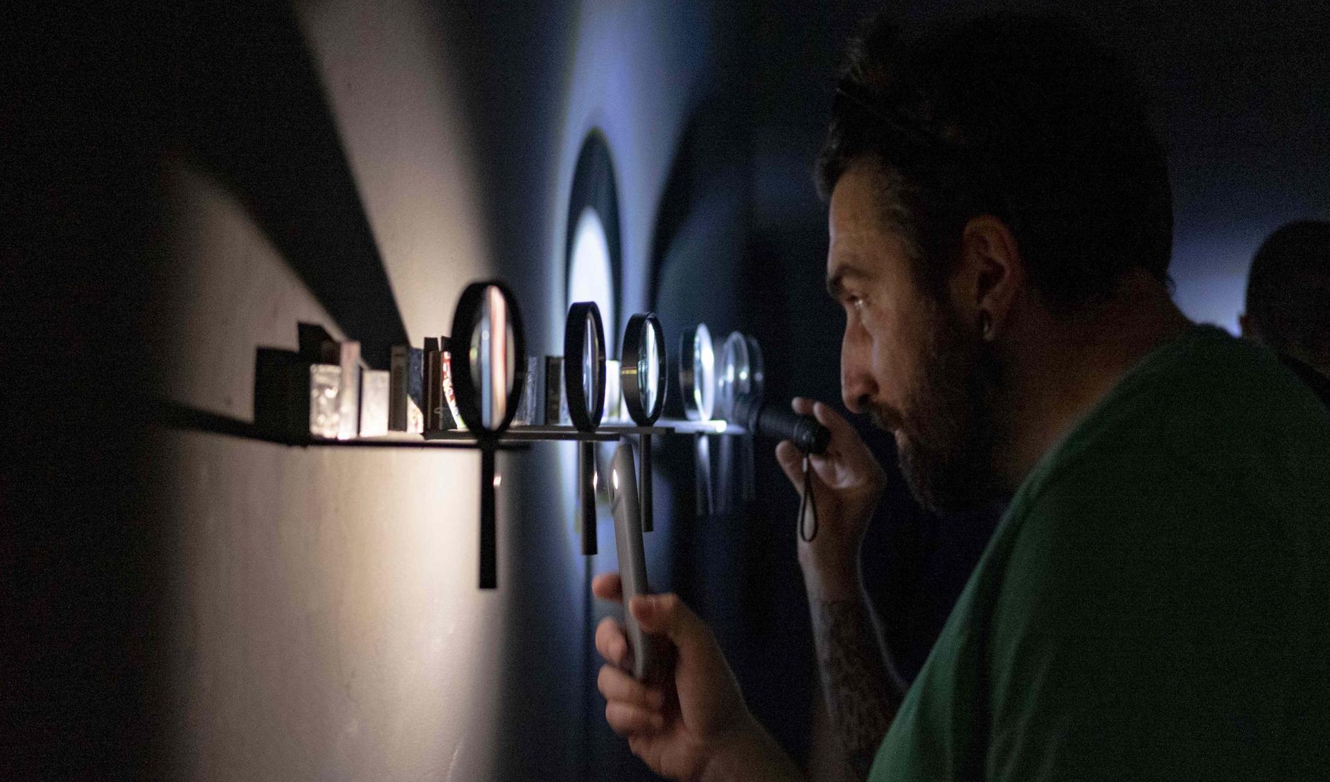 A man is looking thorugh a lighted lens during an exhibition