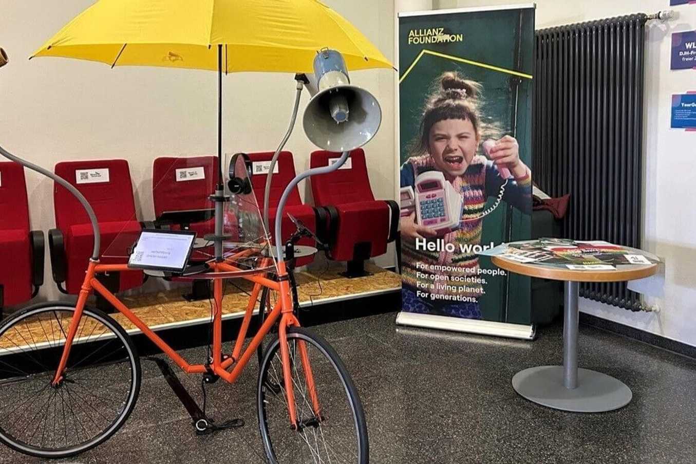 The polling booth reminds a bicycle with three wheels, speakers, touchpads and an yellow umbrella