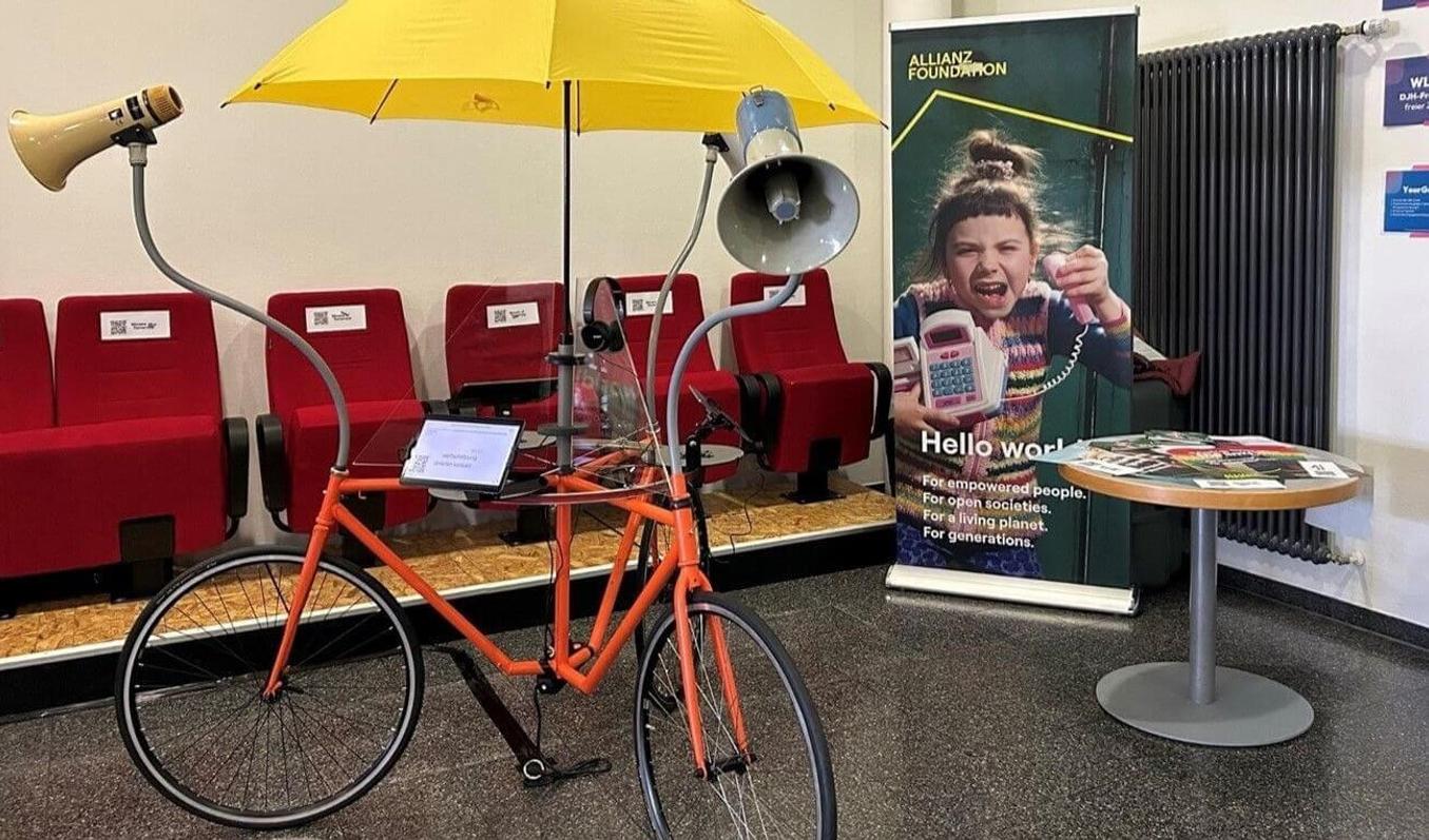 The polling booth reminds a bicycle with three wheels, speakers, touchpads and an yellow umbrella