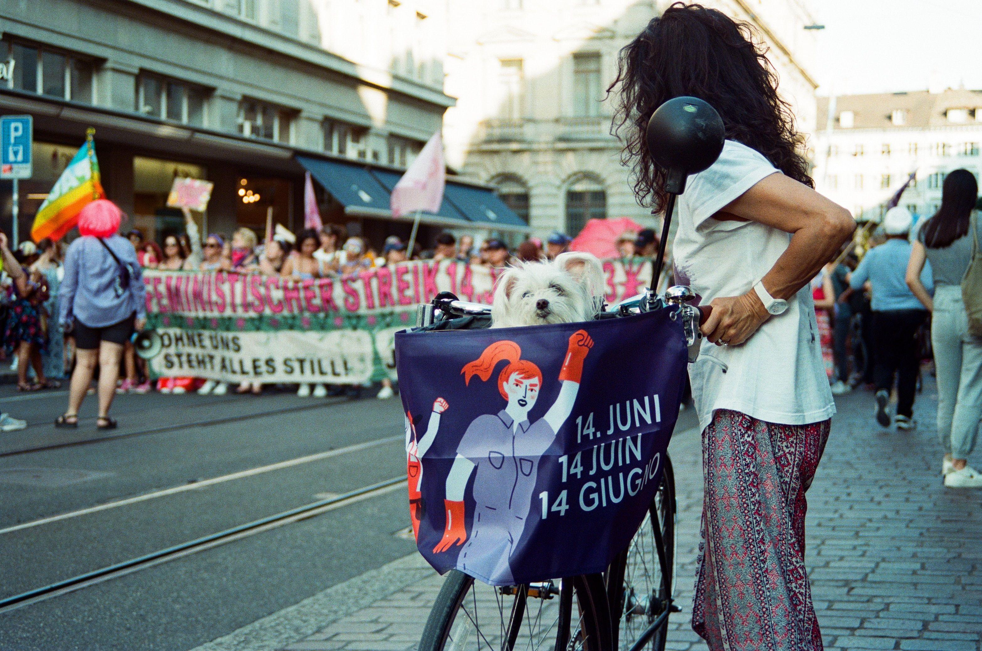 A woman is standing next to a demonstration and is holding her bycycle.