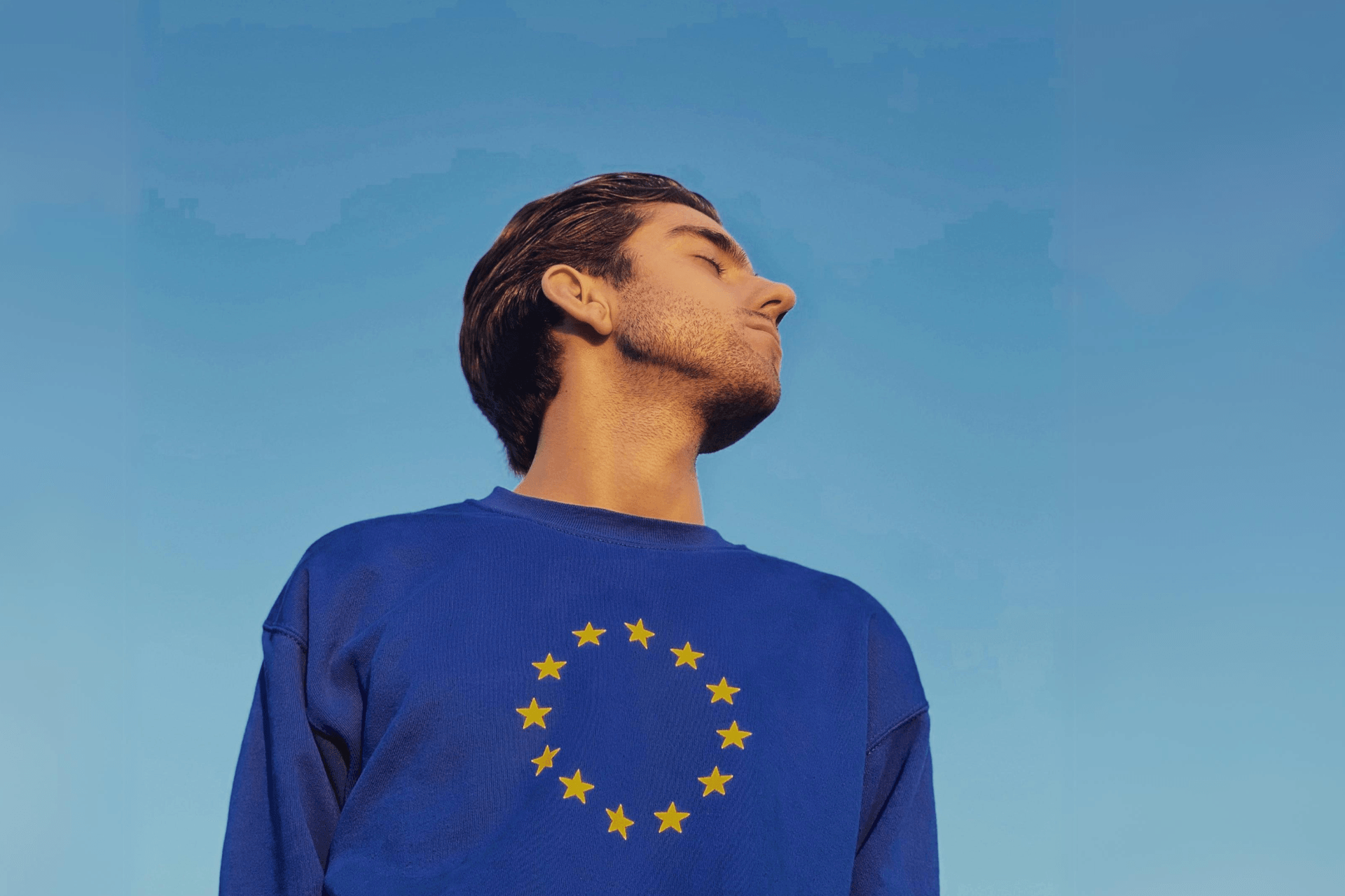 Person wearing EU pullover with their head turned to the sky