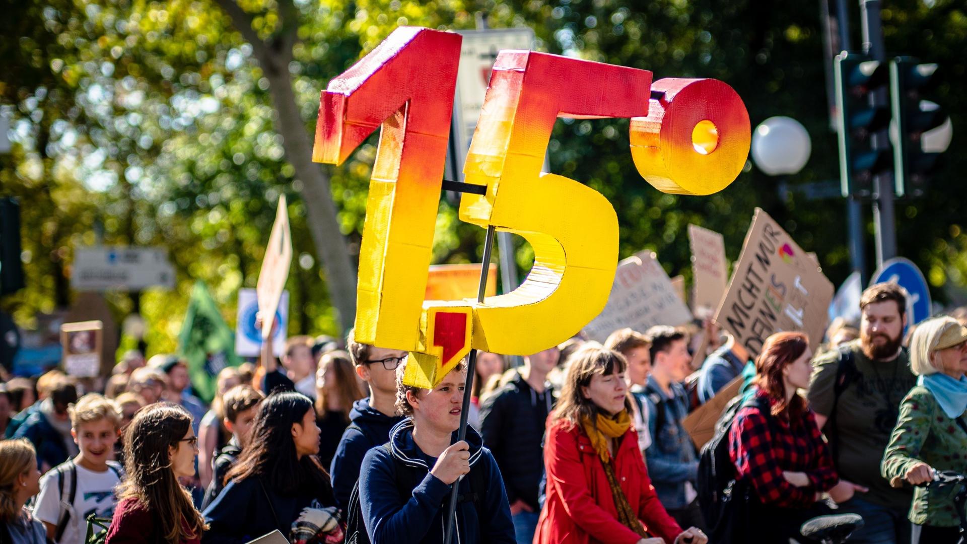 A climate protest. One person holds a sign that states1,5 degrees
