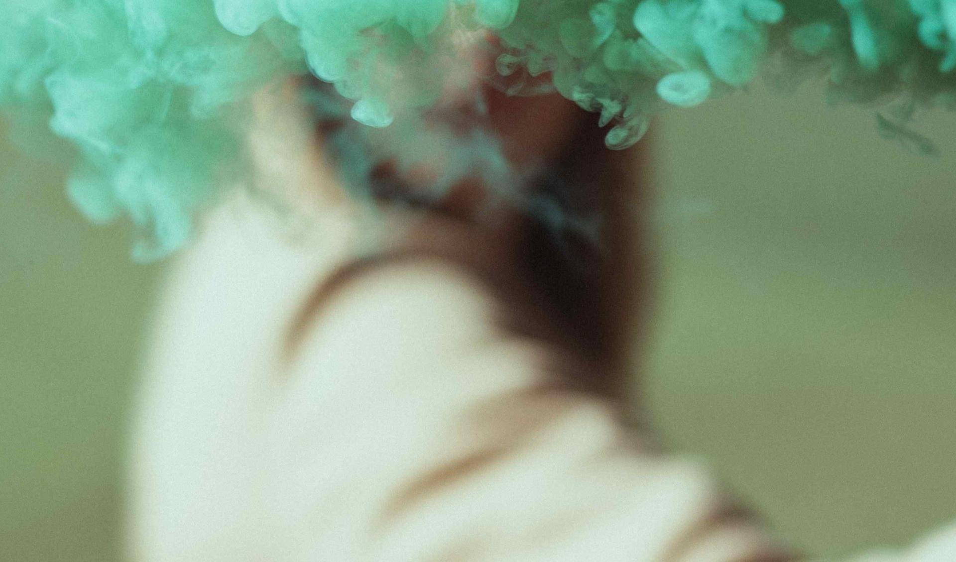 A person with green smoke in front of their face