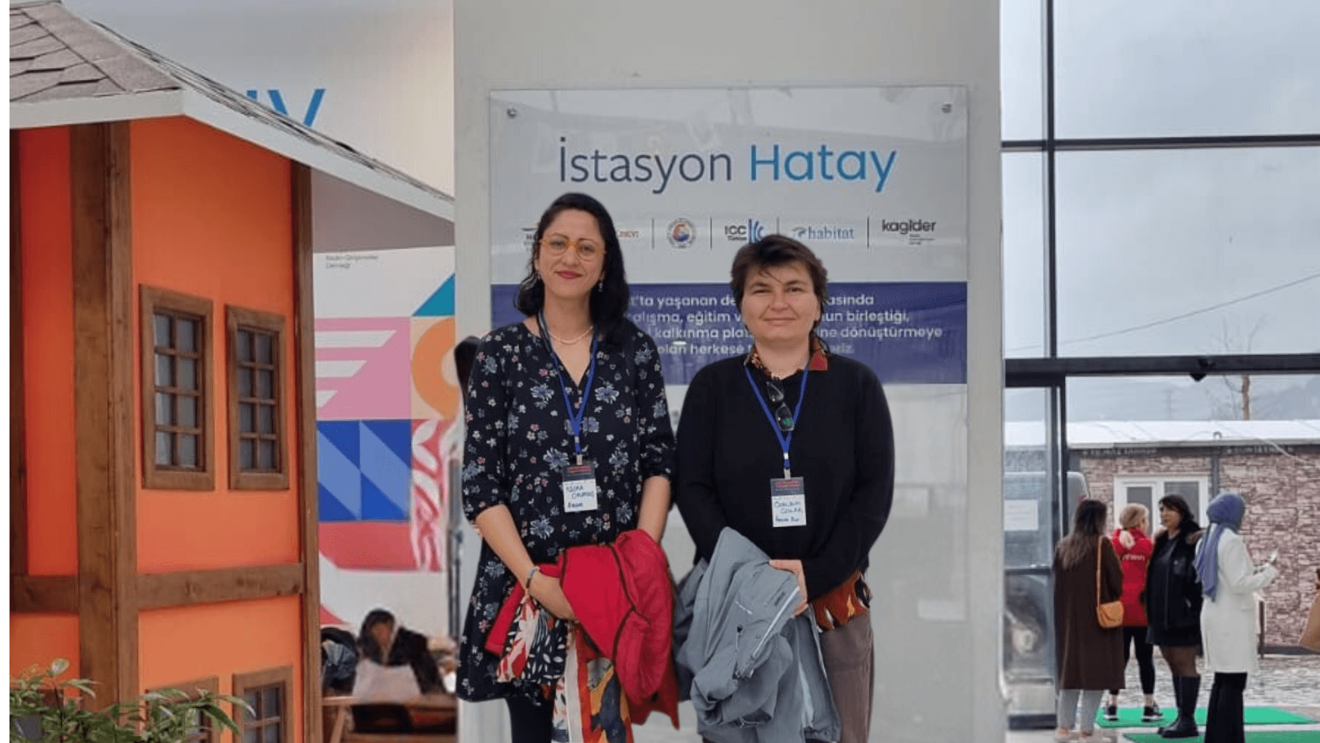 Two people standing in front of "istasyon Hatay" sign