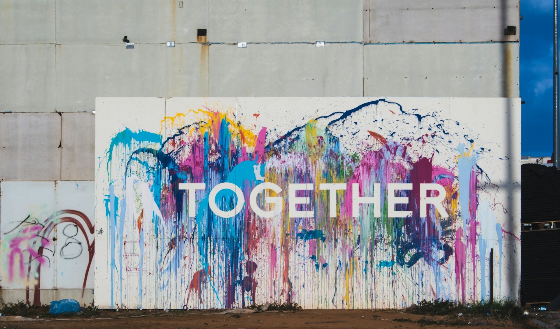 A wall is painted with many colours and its written on it "Together"
