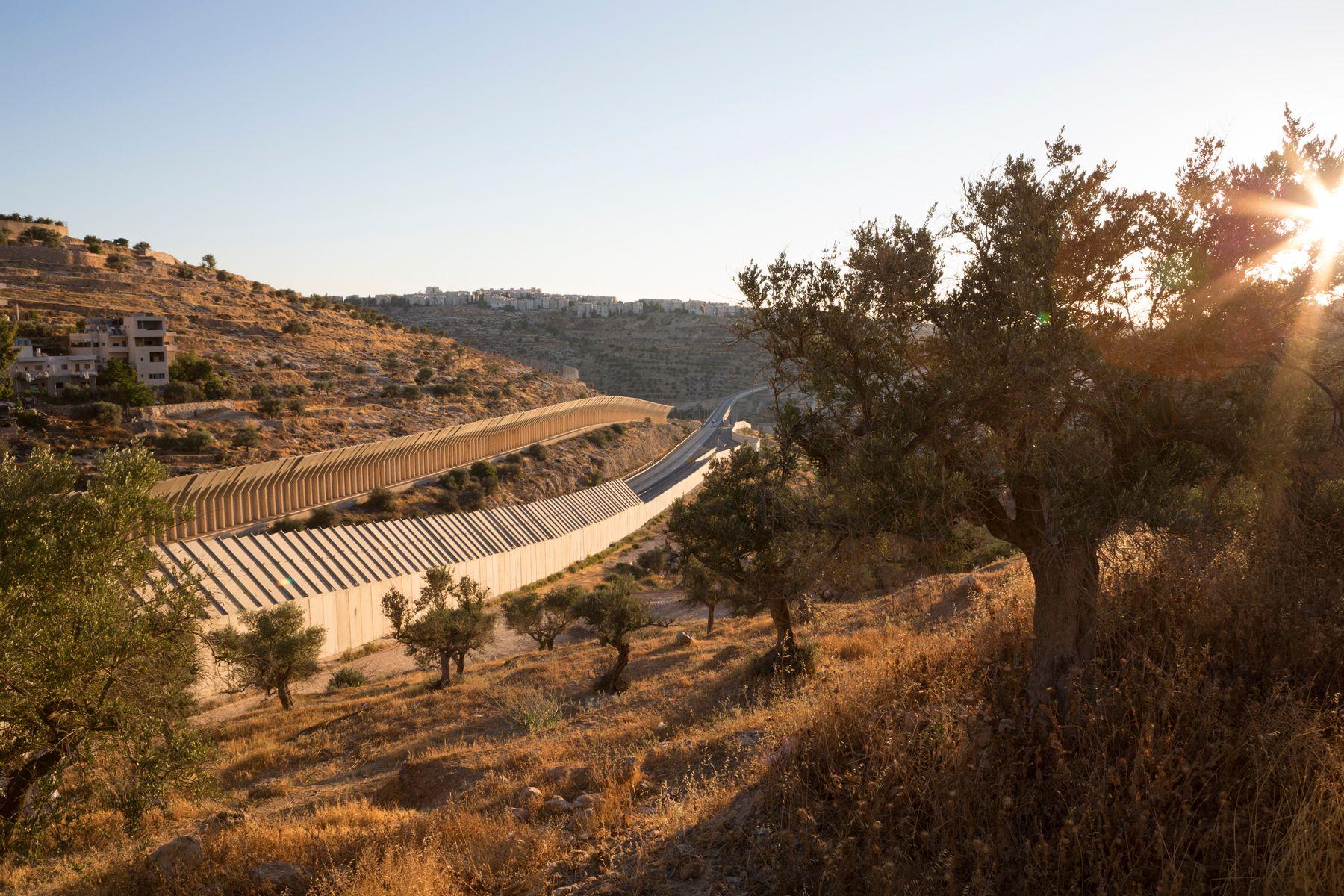 Sunset in the Occupied Palestinian Territories. The Seperation Wall cuts through an valley. Two heavy concrete walls cut through the landscape.